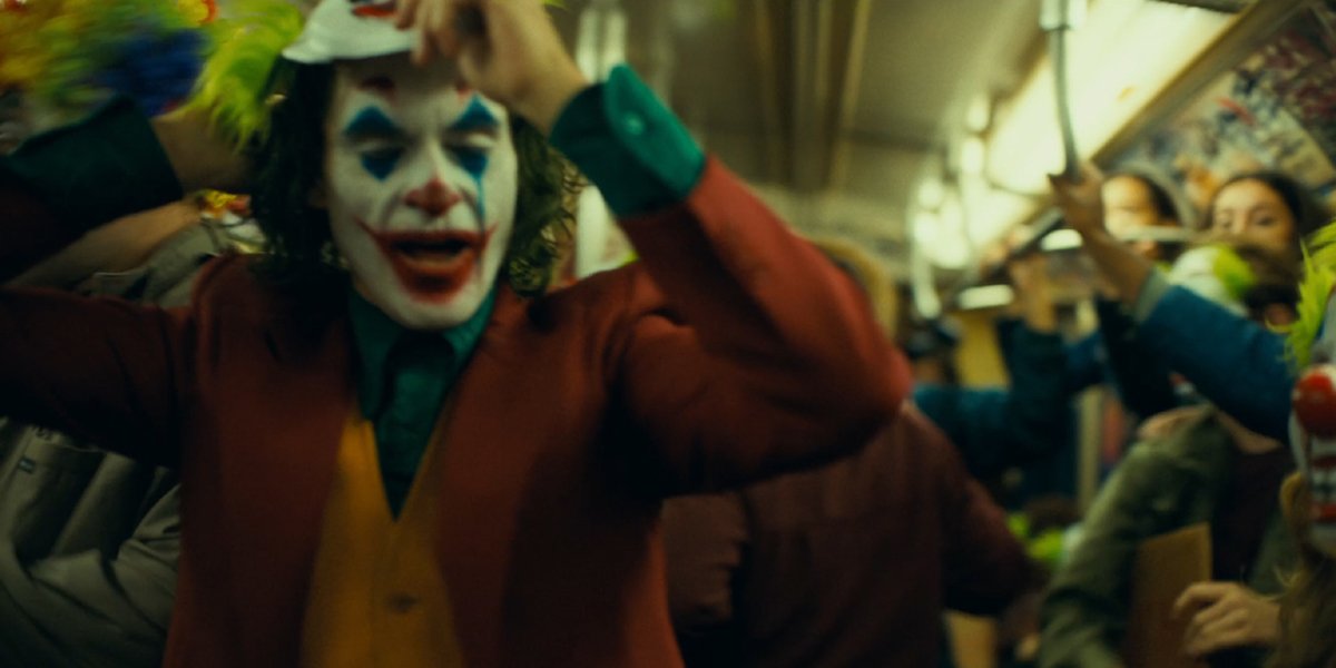 Joker puts on a clown mask in the subway