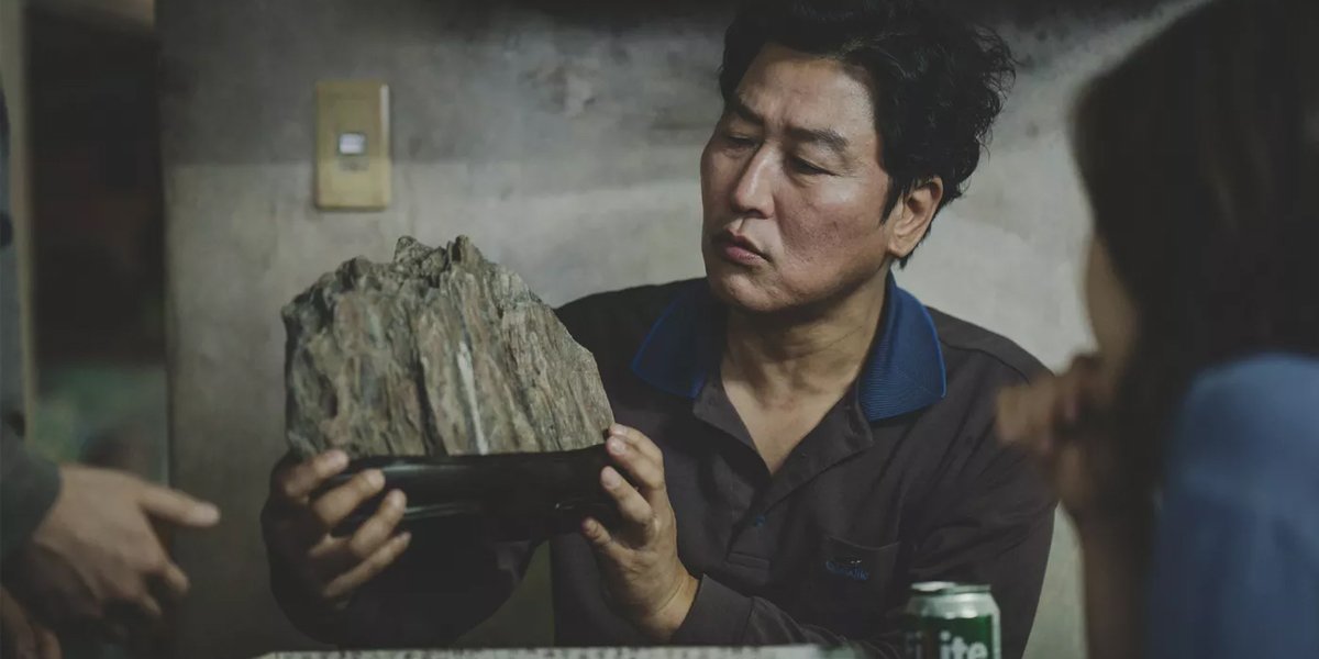 Kang-ho Song holding a Scholar Rock in Parasite