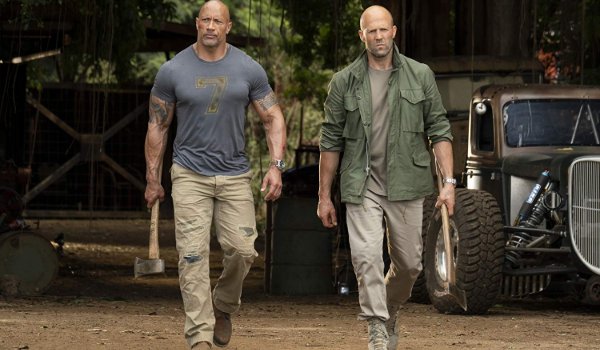 Hobbs and Shaw heading out of the Hobbs garage, weapons in hand