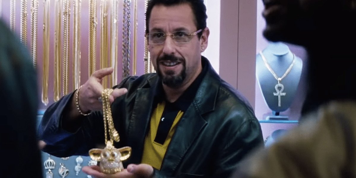 Adam Sandler holding a Furby necklace in Uncut Gems