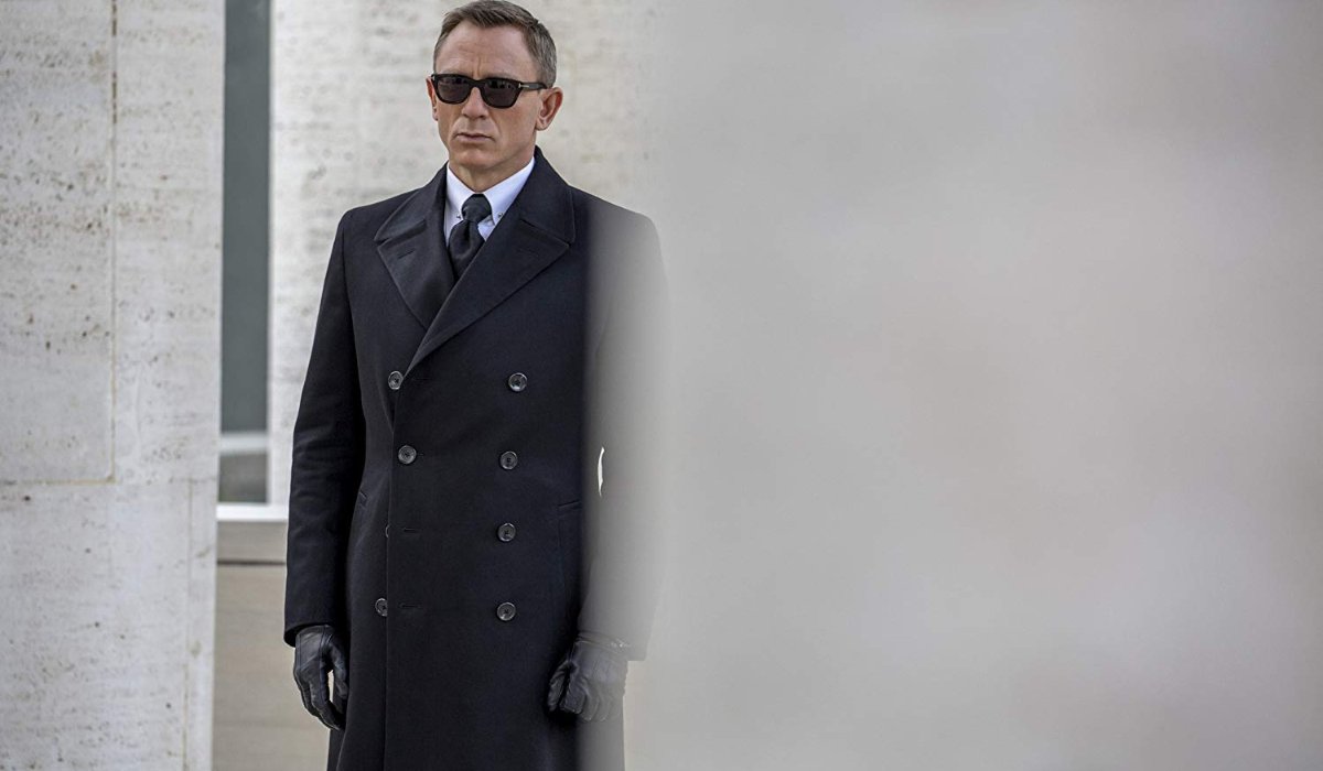 Spectre Bond standing at funeral sunglasses black coat