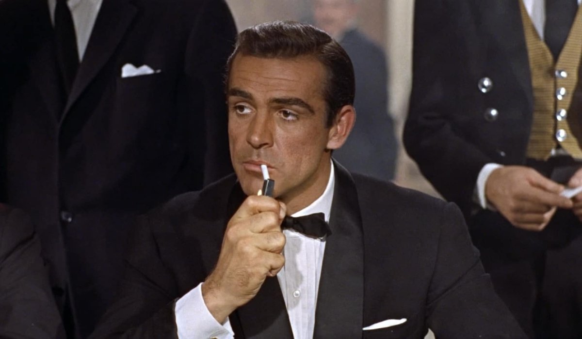 Dr. No Sean Connery lights a cigarette at a card table
