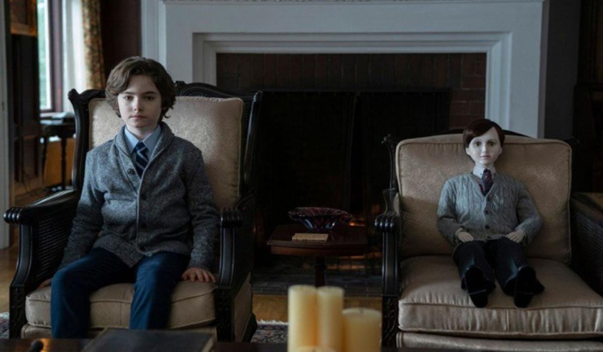 Brahms: The Boy II a young boy and a doll sit dressed identically in the living room